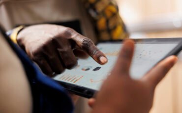 Warehouse worker hand pointing at inventory statistics on tablet