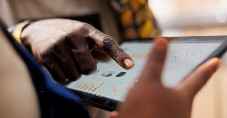Warehouse worker hand pointing at inventory statistics on tablet