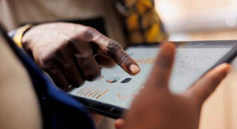 Warehouse worker hand pointing at inventory statistics on tablet